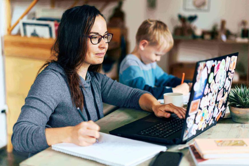 母親和兒子在桌上用筆記本電腦工作