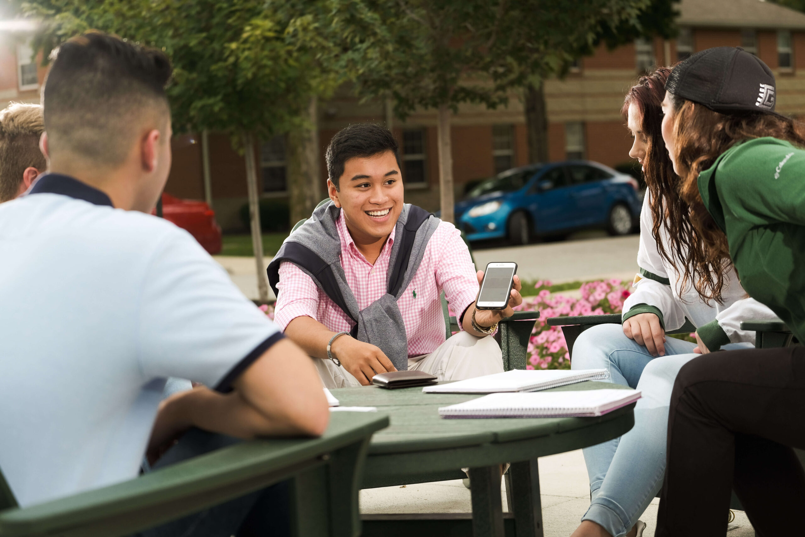 四個大學生坐在戶外的一張桌子旁